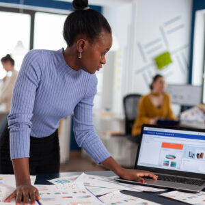 African woman scorlling on laptop looking at charts